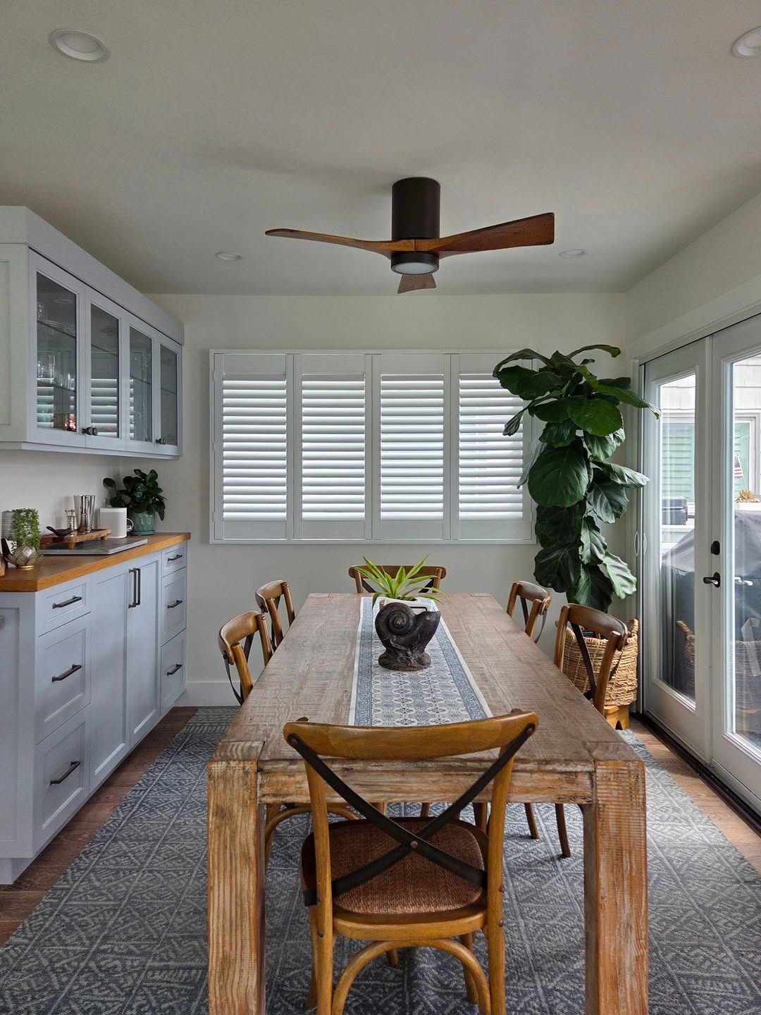 White plantation shutters on a wide window in a farmhouse-style dining room
